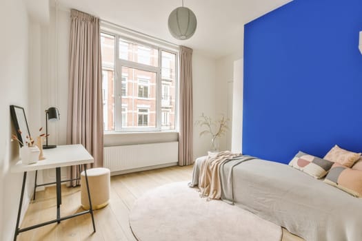 a bedroom with blue walls and white furniture in front of a bed, desk, chair, mirror and window