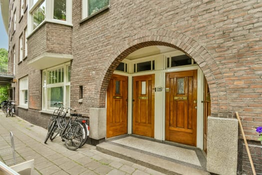 a brick building with two bikes parked in the doorways and one bike leaning against the wall on the other side