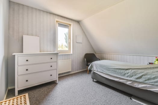 a bedroom with a bed, dresser and window in the attic house stock photo - 1237896