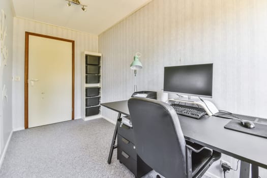 an office space with a computer, monitor and keyboard on the desk in front of the door to the room