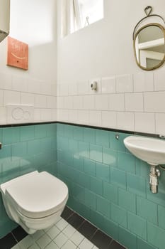 a bathroom with blue tiles on the walls and white fixtures in the toilet bowl is next to the sink basin