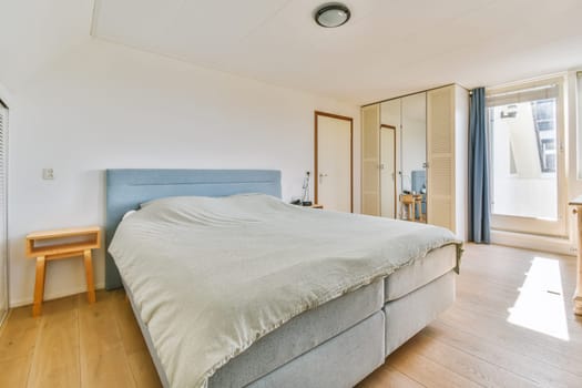 a bedroom with a bed, desk and window looking out onto the street from the living room to the balcony