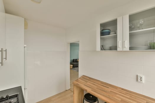 a kitchen with white cabinets and wood counter tops in the center of the room, while there is an open door on the right