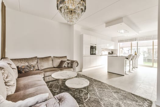 a living room with couches, coffee table, and chandels on the wall in the kitchen area