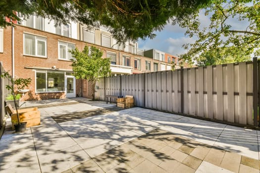 a back yard with a fence and some potted plants on the ground in front of an apartment block building