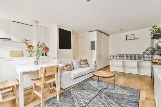a living room with a couch, dining table and small kitchen area in the corner between it to the bed