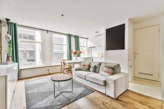 a living room with wood flooring and green drapes hanging on the wall behind it is a white couch