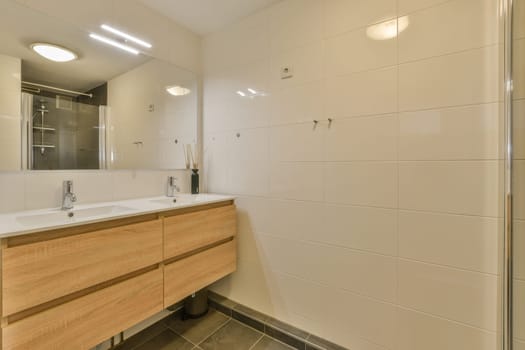 a modern bathroom with wood cabinets and white tiles on the walls, along with a large mirror in the corner