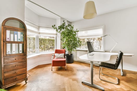 a living room with a red chair and a white desk in the photo is taken to the right, while it's not
