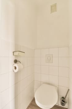 a white toilet in a small bathroom with wood flooring and tile on the walls there is a trash can be seen