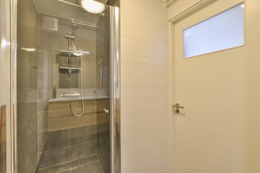 a bathroom with a glass shower door and white tiles on the wall behind it is a toilet in front of a window