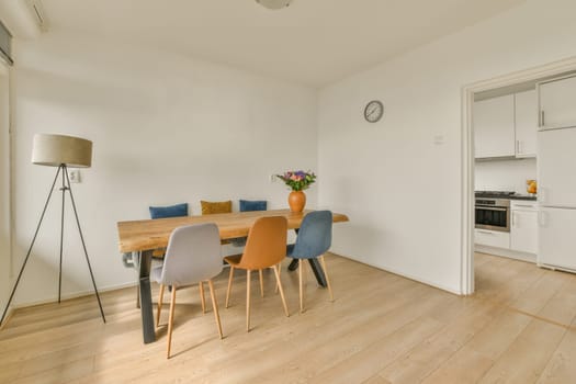 a dining table and chairs in a room with white walls, hardwood flooring and light colored furniture on the right side