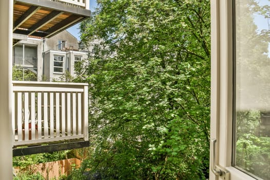 the outside of a house with trees and bushes in front of it, as seen from inside an open window