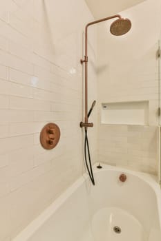 a bathtub and shower head in a bathroom with white tiles on the wall behind it is a shelf for books