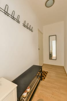 a living room with white walls and wood flooring on the wall, there is a mirror hanging above it
