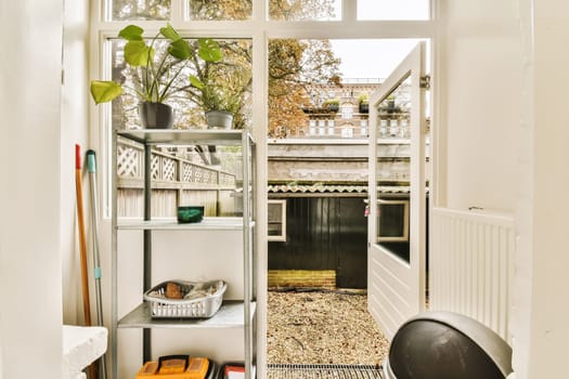 the inside of a house with lots of plants and tools in it, including an open door that leads to a small garden