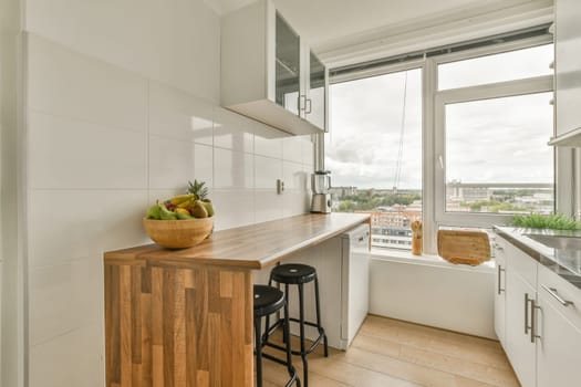 a kitchen with white cabinets and wood counter tops in front of a large window that looks out onto the city