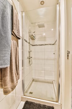 a bathroom with towels hanging on the wall and a glass shower door in the corner, next to a towel rack