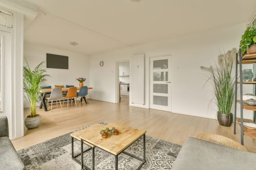 a living room with white walls and wood flooring, there is a tv on the wall in the corner