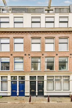 an old brick building in amsterdam, with blue doors on the front and windows open to let you into your home