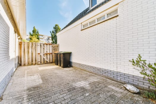 an empty back yard with white brick walls and green trees in the area is surrounded by grey bricks, blue sky