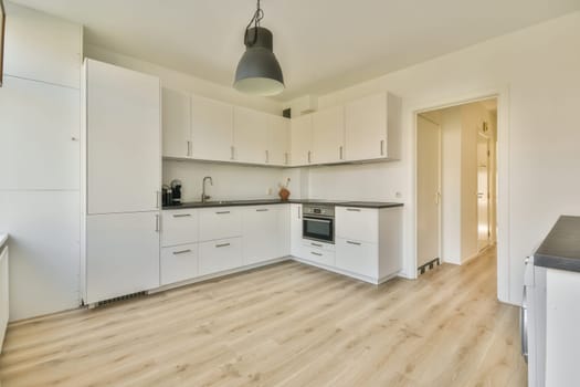 a kitchen area with white cabinets and wood flooring in the middle of the room, there is a black light hanging over the