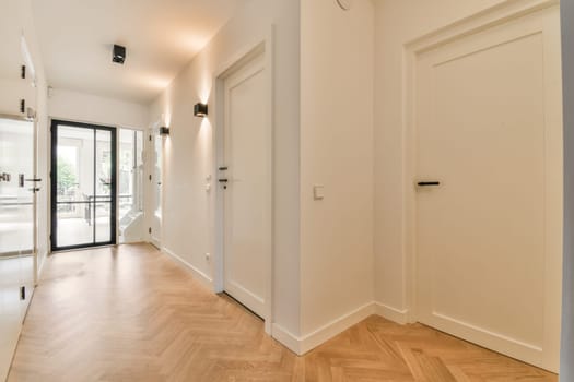 an empty room with wood flooring and white walls on either side, there is a black door in the corner