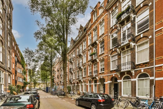some cars parked on the side of a street in an urban area with many bricked buildings and trees lining both sides
