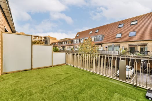 an outside area with green grass and white fenced in to the back side of a brick house on a sunny day