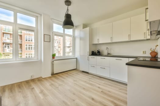 a kitchen area with wood flooring and white cabinetry, including an island style sink and dishwasher