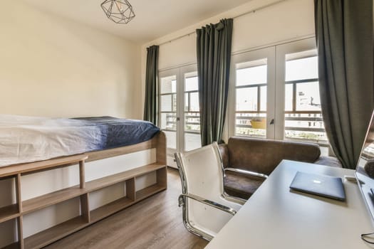 a bedroom with a bed, desk and chair in front of the window that looks out to the city outside