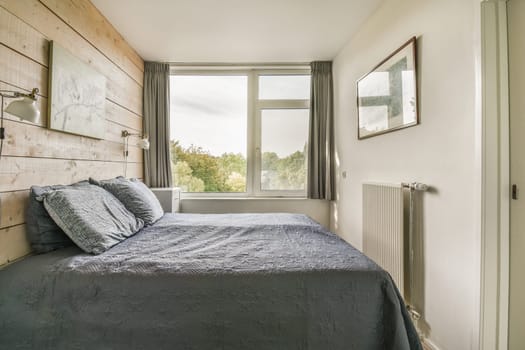 a bed in a room with wood paneling on the wall and window overlooking out onto the street below it