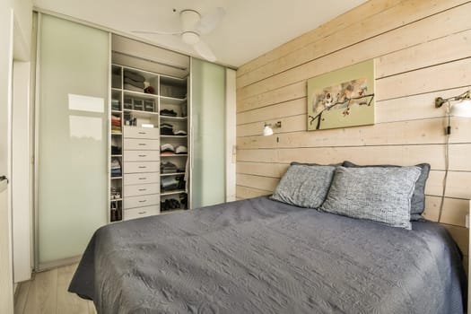 a bedroom with wood paneling on the walls, and a bed that has a blue comforter in it