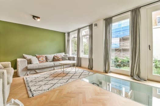 a living room with green walls and wood flooring in the center of the room is an indoor swimming pool