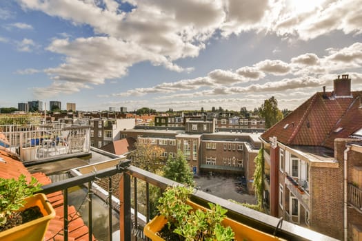 a city from the balcony with clouds in the sky and plants growing on the balknotn, netherlands
