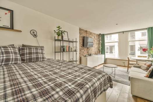 a bedroom with a bed, couch and tv on the wall in it's corner room next to an open window