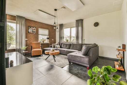 a living room with couches, chairs and plants in the center of the room there is a brick wall that has been painted