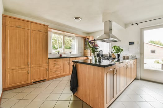a kitchen with wood cabinets and black counter tops on the island in front of the stove hood, which is hanging from the ceiling