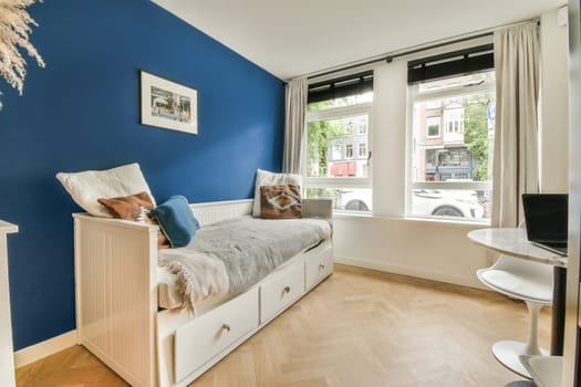 a kid's room with blue walls and white furniture, including a small bed in front of the window