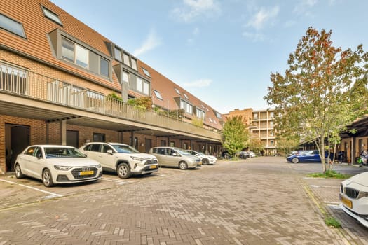 some cars parked on the side of a road in front of a row of apartment buildings with balknight windows