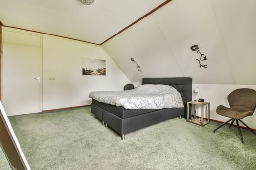 a bedroom with a bed, chair and desk in the corner next to the window on the left is an open door