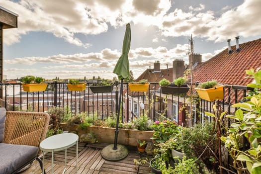 a balcony with chairs and umbrellas on the roof, some potted plants are in front of the chair