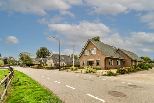 a house on the side of the road with clouds in the sky and green grass growing along the curb area