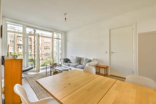 a dining table and chairs in a living room with sliding glass doors that open onto the balcony area to an outside patio