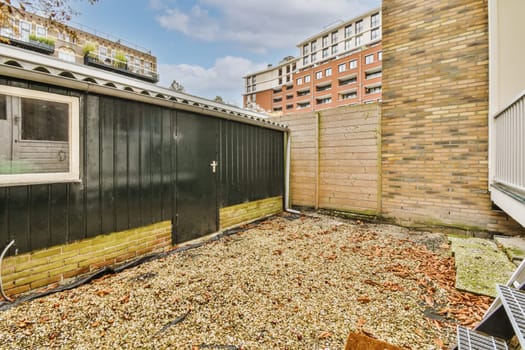 an outside area with some leaves on the ground and brick buildings in the background photo is taken from behind it
