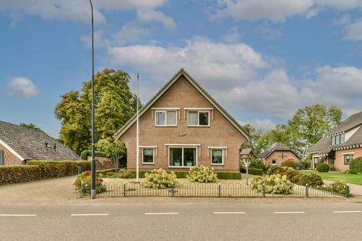 a house that is in the middle of a residential area with trees and bushes on either side of the street