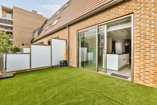 an outside area with green grass and brick walls, including sliding glass doors to the left side of the house