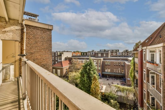 a balcony with some buildings in the background and blue sky above it, as seen from an apartment building window