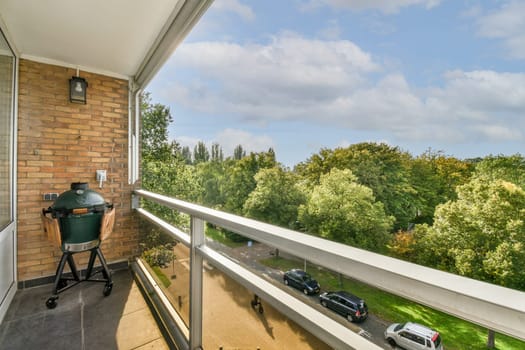 an outside area with a grill on the balcony and cars parked in the yard behind it, there is a blue sky filled with