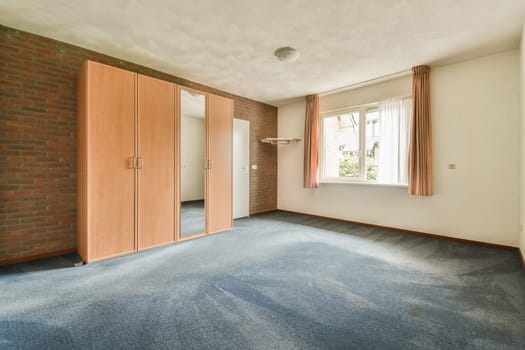 an empty room with brick walls and blue carpet in the middle of the room, there is a mirror on the wall